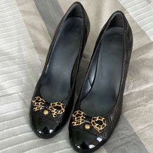 Stuart Weitzman quilted patent leather pumps with gold detail.